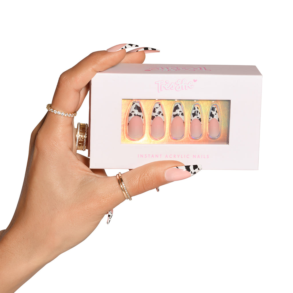 Hand holding box of cow print French tip nails, wearing cow print French tip nails