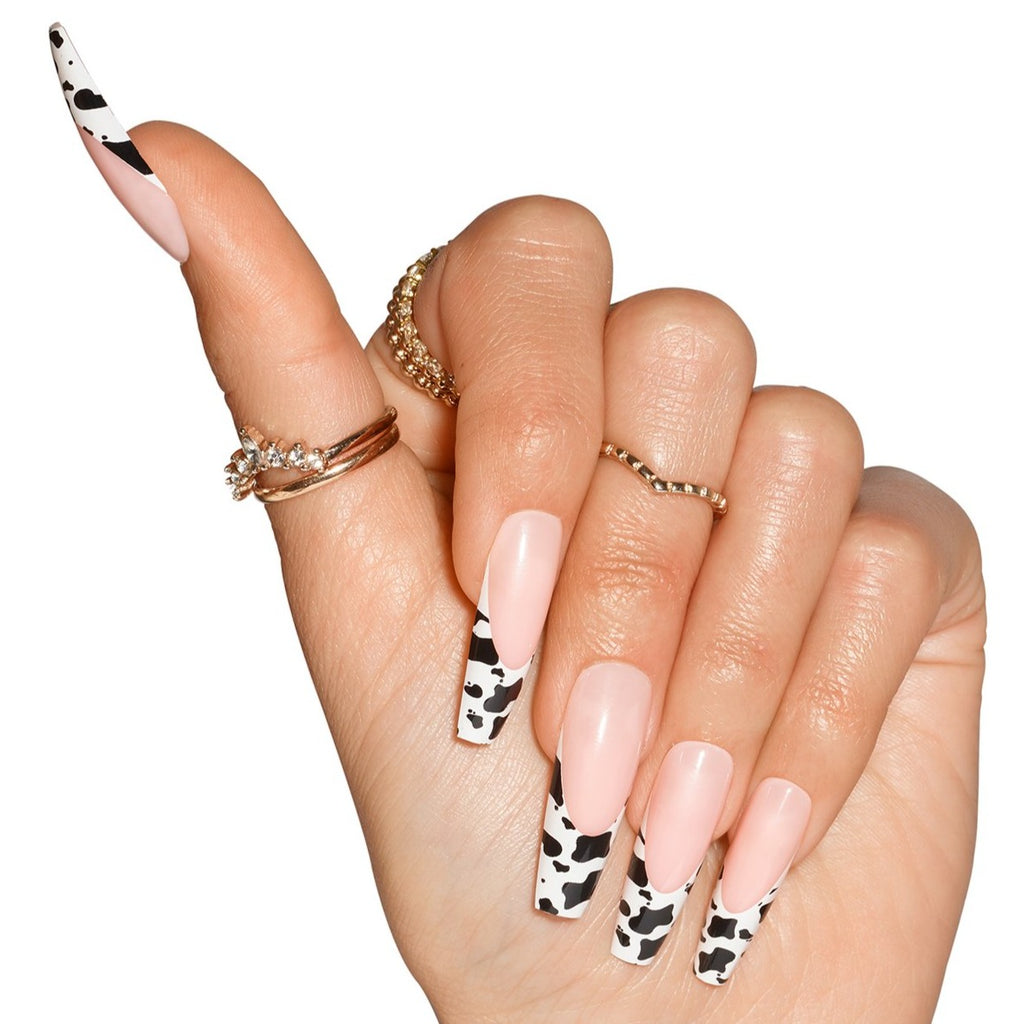 Hand wearing Big Moood nails, natural french with cow print on tip, in coffin shape ultra long length