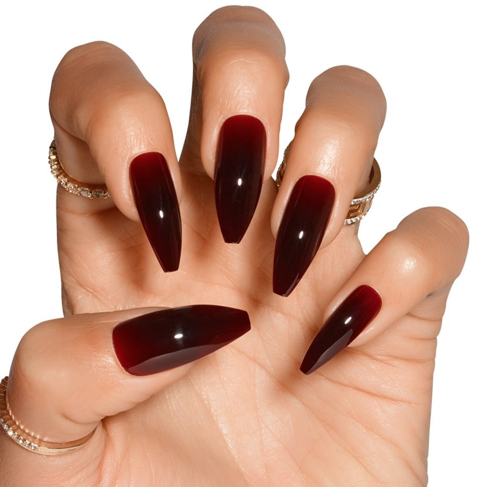 Claw hand wearing Tres She Cherry Cola dark red jelly nails, ballerina shape long length