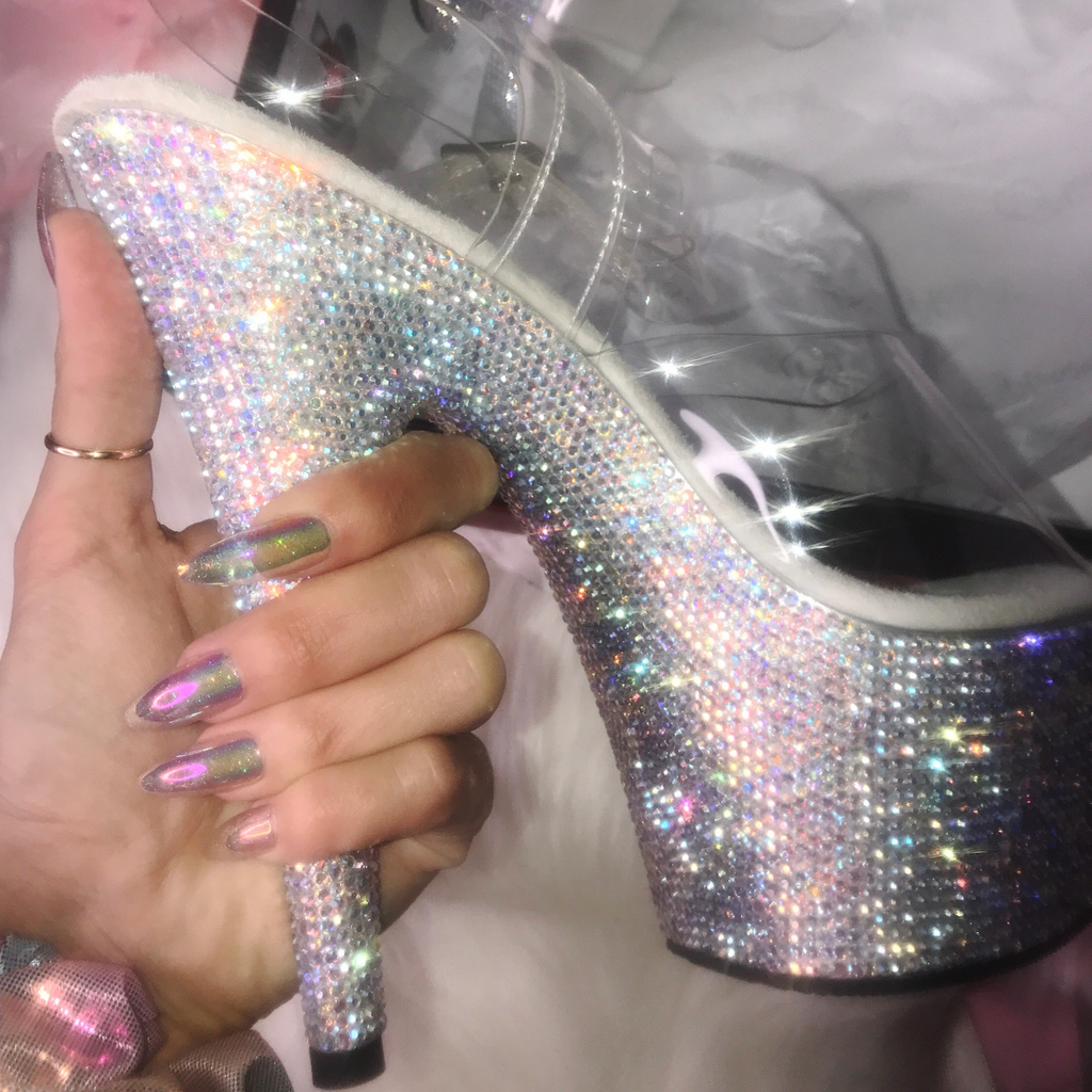 Hand wearing press on holographic and iridescent glitter nails holding stripper heel shoe with rhinestones 
